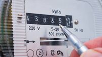 Ballpoint pen in person's hand showing electricity meter readings.